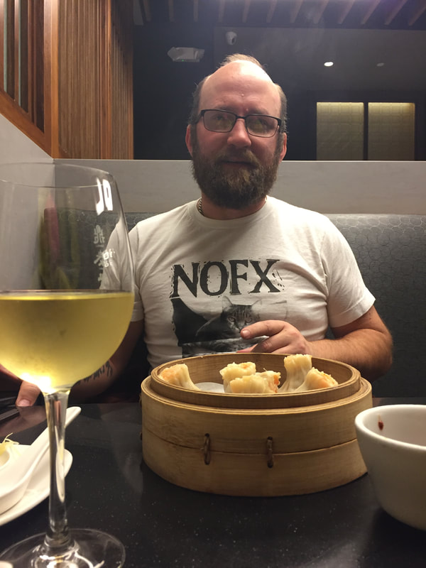 Man with beard and glasses eating Chinese dumplings.